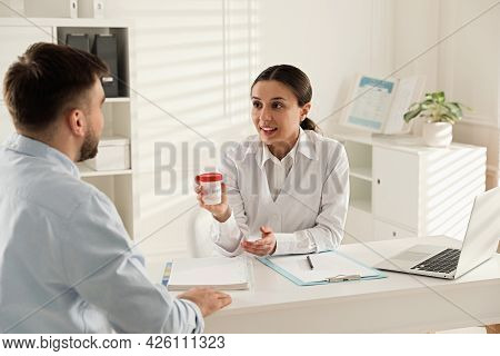 Donor Giving Container Of Sperm To Doctor In Hospital