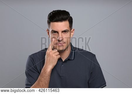 Man Checking His Health Condition On Grey Background. Yellow Eyes As Symptom Of Problems With Liver