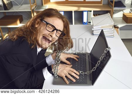 Tired Office Worker Sitting At Desk Chained To Laptop And Crying Unable To Go Home