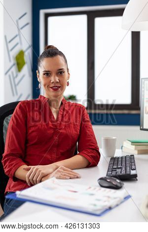 Portrait Of Start Up Enterprise Company Leader Smiling At Camera While Doing Financial Paperwork. Su