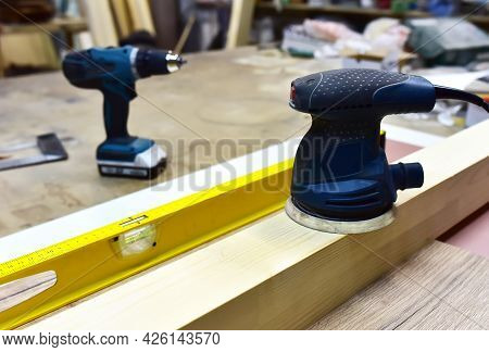 Electric Wood Sander On Wooden Table In Workshop. Woodworking Tool Concept. Furniture Metal Polisher