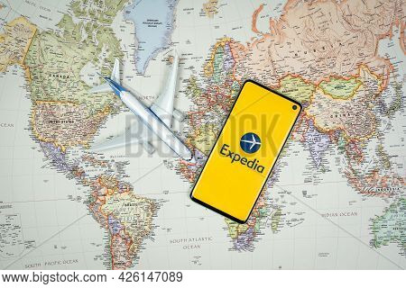 Expedia Application Logo On Mobile Phone Screen With Plane And World Map