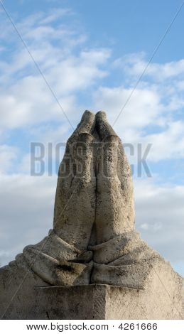 Statue de mains priant au bleu ciel