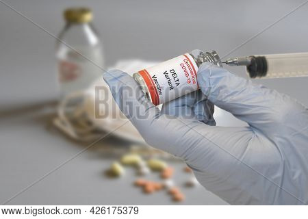 Covid-19 Delta Variant Vaccine. The Hand Of The Doctor With A Blue Glove Holds The Syringe And The H