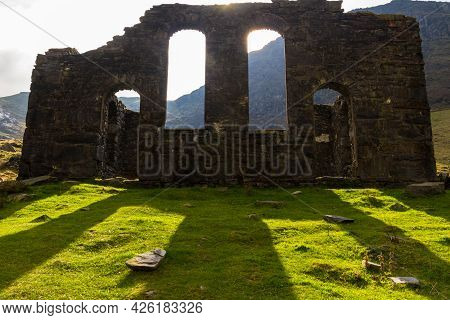 Spectacular Sun Behind Ruined Gothic Church, Throwing Light Onto Green Grass.