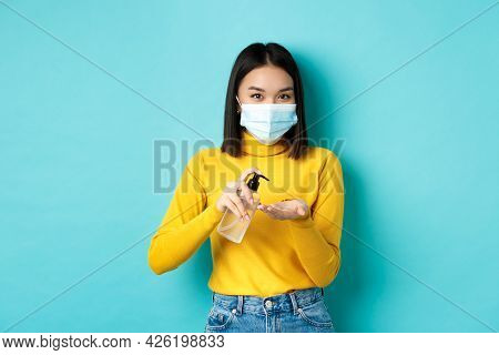 Covid-19, Social Distancing And Pandemic Concept. Smiling Asian Woman In Medical Mask Using Preventi