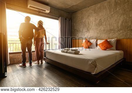 Portrait Of Young Couple Tourist Standing Nearly Window, Looking To Beautiful View Outside In Hotel/