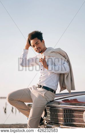 Young Black Man In Nature Posing With A Convertible. Sunset Portrait.