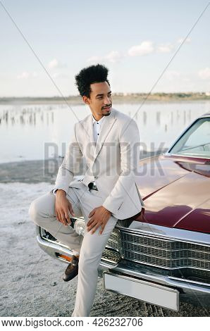 Young Black Man In Nature Posing With A Convertible. Sunset Portrait.