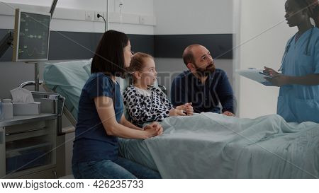 African American Pediatric Asisstant Monitoring Sick Child Discussing Recovery Treatment With Parent