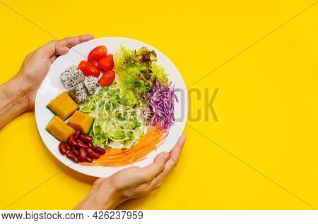 Hands Holding A Plate Of Vegan Salad On Yellow Background For Vegetarian Festival In Thailand.