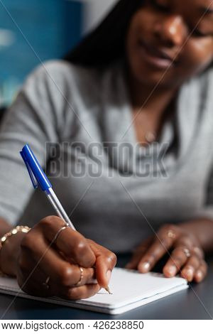 Closeup Of Student With Black Skin Writing Education School Homework On Notebook While Sitting At De