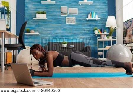 Athletic Fit Black Woman In Leggings Sitting On Yoga Mat Doing Plank Pose, Exercising Core Abdominal