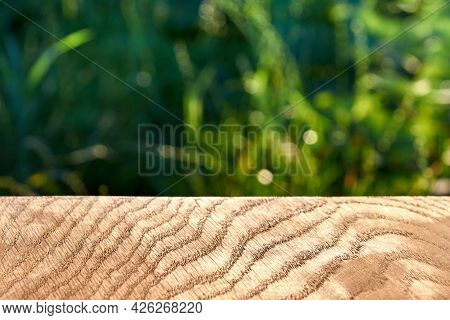 Wooden Texture, Smooth Oak Surface, Grass In The Background Out Of Focus, Close-up.