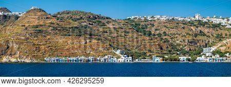 Panorama of Klima and Plaka villages with whitewhashed traditional houses and orthodox church and windmills on Milos island, Greece