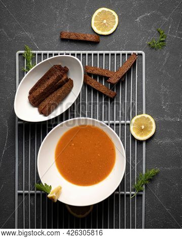 Bowl Of Orange Curry Soup And Rye Bread Croutons. Flat Lay. Top View Of Food Plate At Grill Grid On 