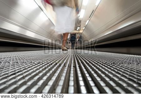 Low Angle View Of A Female Commuter Walking On Moving Walkway