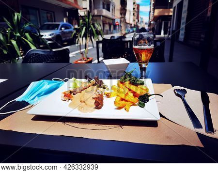 Medical Mask On The Serviced Table. Work Of The Cafes And Restaurants During Covid-19 Pandemic