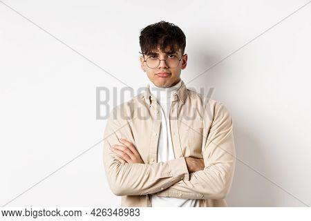 Image Of Stylish Hipster Guy In Glasses Feeling Bored, Looking Unamused With Pokerface, Cross Arms O