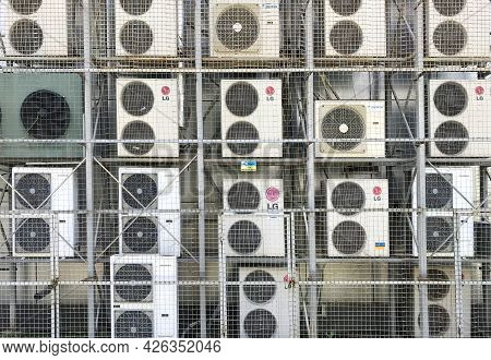 Lots Of Air Conditioners On The Wall Of The Building Covered With The Metal Grid. There Are Lg, Daik
