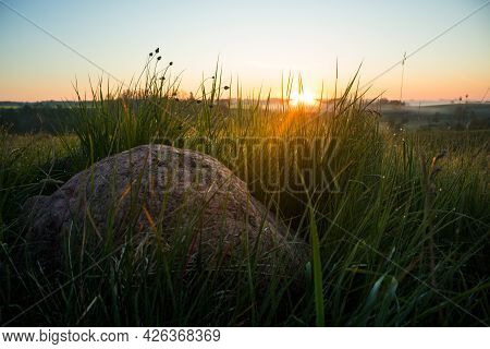 Sunrise Landscape With Roks On The Siede Of The Meadow And Field. Summertime Scenery Of Northern Eur