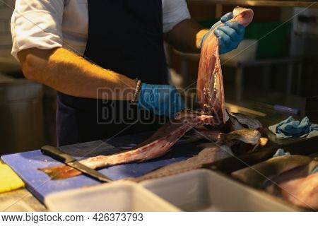 The Chef Cuts The Fish In Blue Gloves