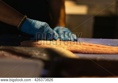 The Chef Cuts The Fish In Blue Gloves