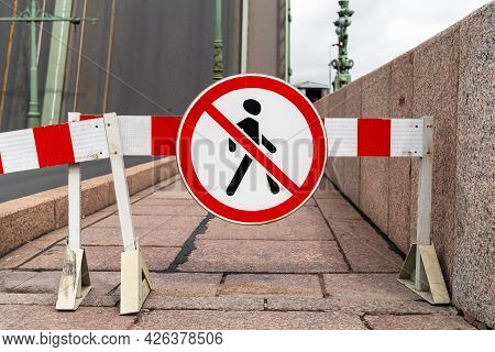 Barrier Blocking Sidewalk And Sign With Picture Of Crossed-out Man Prohibiting The Passage Of Pedest