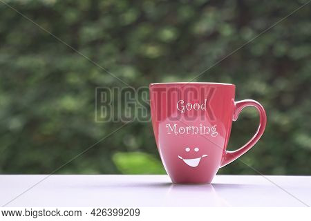 Good Morning Message On Red Coffee Cup, On Green Nature Background. Copy Space.