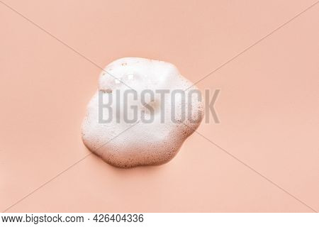 Face Cleansing Mousse Sample. White Cleanser Foam Bubbles On Nude Background. Soap, Shower Gel, Sham