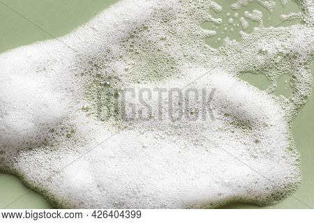Face Cleansing Mousse Sample. White Cleanser Foam Bubbles On Green Background. Soap, Shower Gel, Sha
