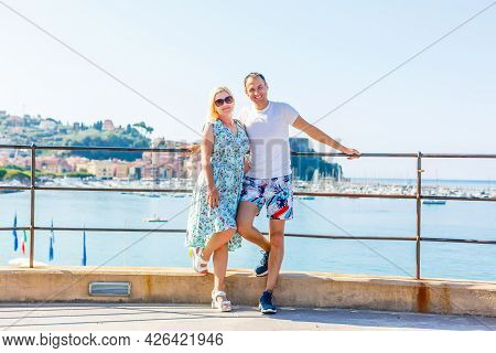 Travel Italy, Europe. Smiling Couple In Love At Lake Garda With Mountains, Lake And Town On The Back