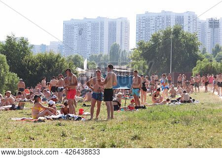 Moscow, Russia - July 2021: Crowd Of People Sunbathing On A Green Lawn On Background Of Residential 