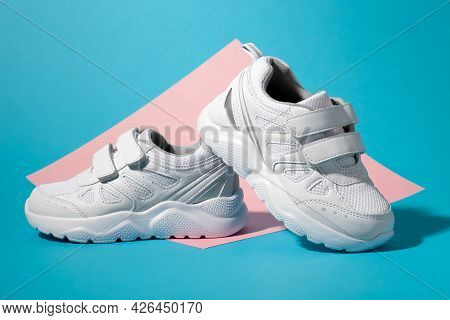 Macro Side View One White Kid Sneaker Stands On The Back Of The Second Sneaker On A Geometric Square