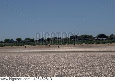 Old Hunstanton, Norfolk, England - June 13 2021. People In The Sand And Water Full Of Bright Reflect
