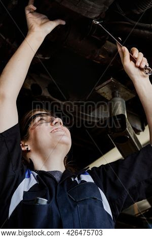 Female mechanic checking the undercarriage of a car