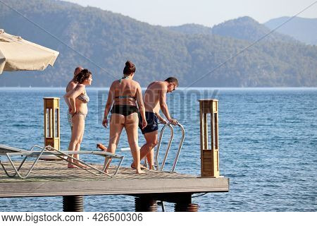 Hisaronu, Turkey​ -​ July 2021: People Having Fun On A Beach On Green Mountains Background. Tourists