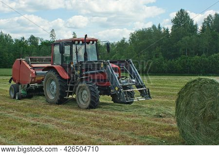 Tractor During Hay Bales Making For Livestock During Field Work On A Farm
