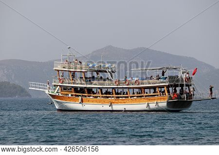 Hisaronu, Turkey​ -​ July 2021: Boat With Tourists Sailing In Aegean Sea On Misty Mountains Backgrou