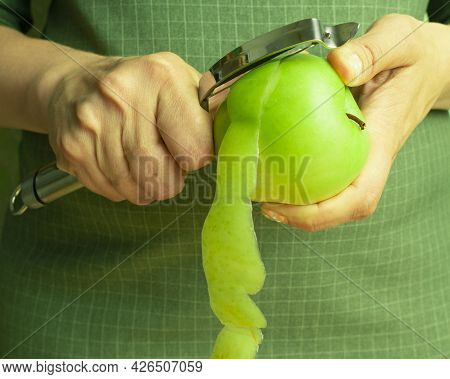 A Woman Peels A Green Apple In Close-up, Cooking Concept.