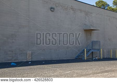 Trash And Waster Litter On The Side Of A Building With Metal Steps And Rails Cinder Block Texture