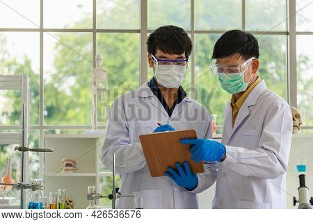 Professional Senior Doctor Scientist Teach And Guide Young Scientist Writing Note To Paper Clipboard