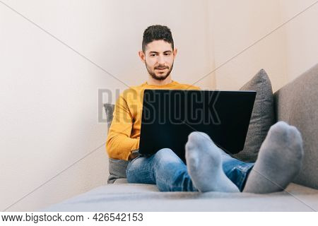 Mid Adult Man Working Remotely From The Sofa At Home. Concept Of Future, Family Balance And Home Wor