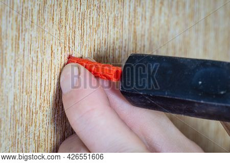 The Male Hand Hammers The Dowel Into The Wall With A Hammer. Dowel Is Hammered Into The Wall, Close-