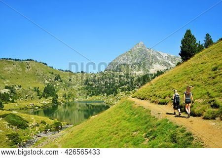 Hikers on a trip in Neouvielle national nature reserve, Lac du Milieu, French Pyrenees. Beautiful summer mountain landscape in the sunny day.
