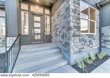 Home Facade With Stone Brick Wall And Gray Front Door With Frosted Glass Panels