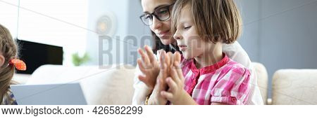 Woman Holds Laptop On Lap Of Little Girl Sitting