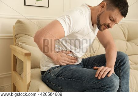 Man Suffering From Pain In Lower Right Abdomen On Sofa At Home. Acute Appendicitis
