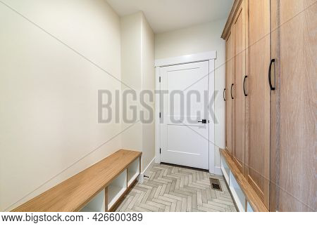 Mudroom Interior With Herringbone Tile Pattern Flooring And Wooden Cabinet