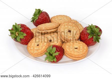 Flat Round Sandwich Cookies With Strawberry Jam Filling Among The Fresh Strawberries On A White Dish